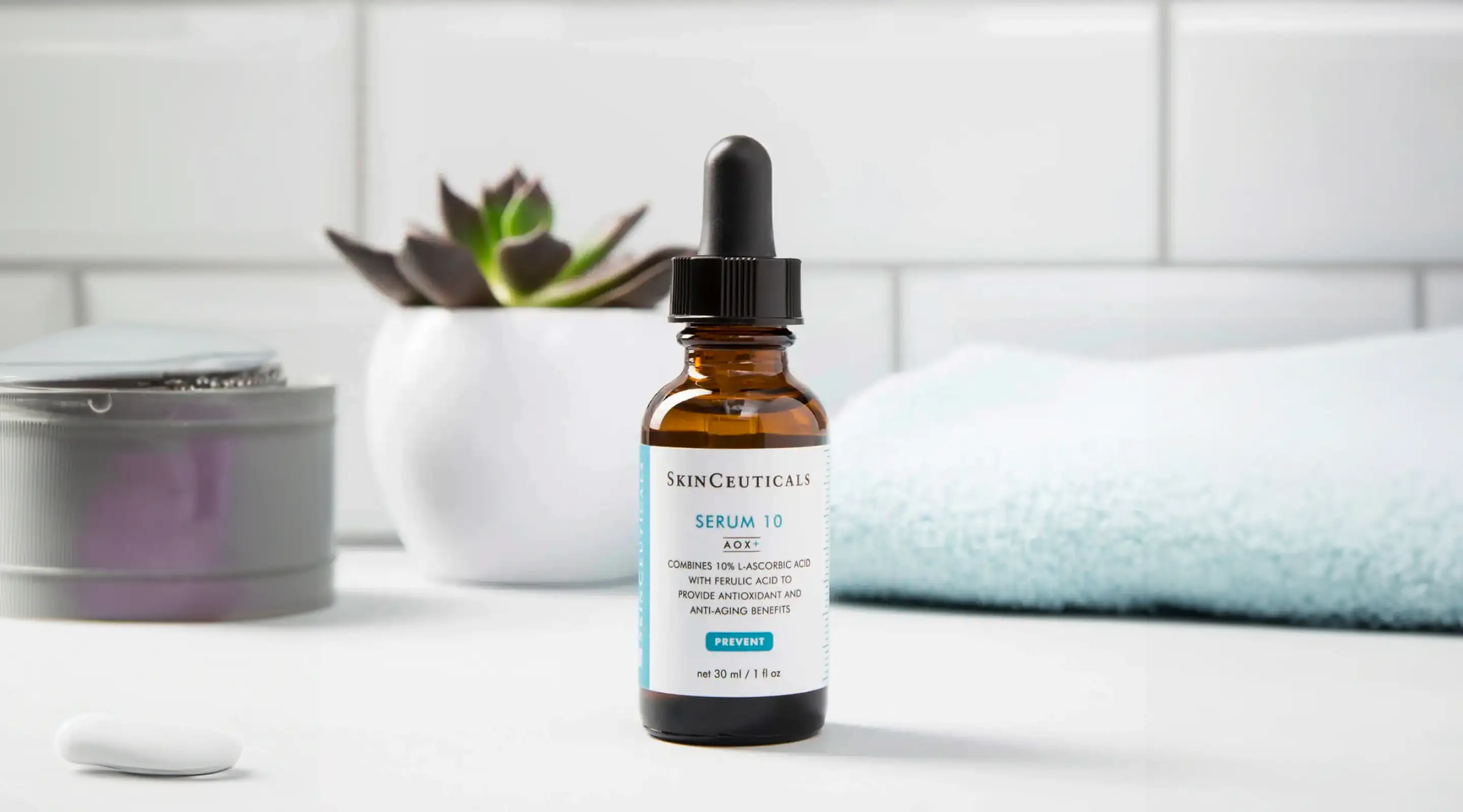 Closeup image of a SkinCeuticals product, Serum 10, on white counter in a bright bathroom, slightly blurred background